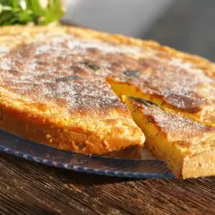 Tarta dorada con azúcar glas, un trozo cortado, como un flao ibiza.