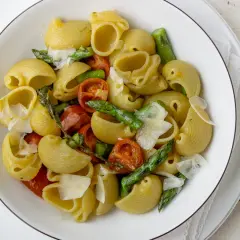 Pyszny makaron ze szparagami i pomidorkami koktajlowymi, posypany parmezanem. Idealne danie na wiosnę.