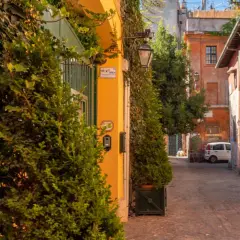 Un vicolo pittoresco tra le vie di Roma centro, con edera rampicante, edifici colorati e un'auto bianca parcheggiata.