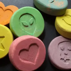 Kolorowe tabletki z symbolami: serce, gwiazda, uśmiech, kosmita, czaszka. Niektóre mogą zawierać mdma.