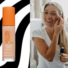 Uśmiechnięta blondynka aplikuje podkład Rimmel Lasting Radiance, który został wycofany.