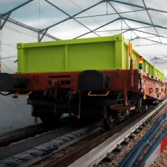 Zielony wagon towarowy na torach pod namiotem. Może to być pierwsza kolej na świecie w takim wydaniu.