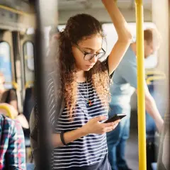 Ragazza sul bus guarda il suo telefono, forse controllando l'orario della metro linea A di Roma per il suo prossimo viaggio.