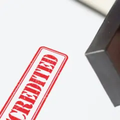 A hand presses a stamp, leaving a red "ACCREDITED" mark. This signifies official MPA accreditation.