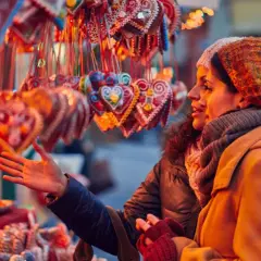 Dos mujeres admiran dulces y galletas en forma de corazón en un mercadillo de Santillana del Mar.