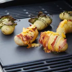 Pommes de terre Hasselback garnies de lard et de fromage, prêtes à cuire sur un barbecue électrique.