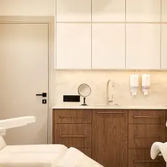 Nowoczesny gabinet dermatologiczny z fotelem zabiegowym, umywalkami i szafkami.