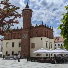 Rynek w Tarnowie z ratuszem i wieżą widokową. Wiosną kwitną drzewa, a kawiarnie zapraszają do ogródków.