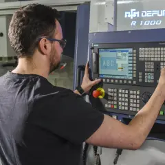 Operator CNC przy panelu sterowania maszyny. Zastanawiasz się, ile zarabia operator CNC w Niemczech?