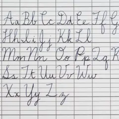 The alphabet in cursive, from A to Z, is written in neat blue ink on lined paper. The handwriting is perfect in cursive, showing each letter's formation.