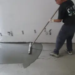 Man behandla betonggolv inomhus med en bredspackel för att jämna ut det flytande materialet.