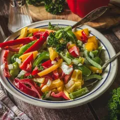 Bunter Salat mit Paprika, Zwiebeln und Petersilie, serviert auf einem rustikalen Holztisch.