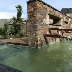La mare aux plantes, avec sa cascade moderne en pierre et métal, invite à la détente. L'eau ruisselle doucement dans le bassin verdoyant.