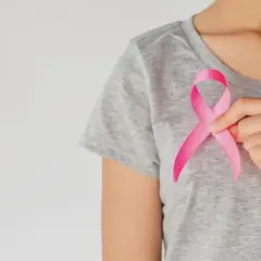 Dłoń trzyma różową wstążkę symbolizującą walkę z rakiem piersi. Wiedza o rodzajach raka piersi jest kluczowa.