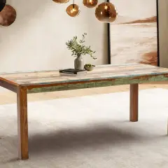 Ein rustikaler Esstisch aus verschiedenen Holzarten mit farbigen Akzenten, der in einem stilvollen Esszimmer steht.