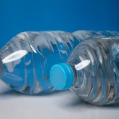 Dwie butelki wody z niebieskimi zakrętkami. Zastanawiasz się, czy można wziąć wodę do samolotu?