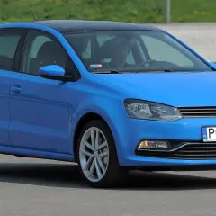 Niebieskie polo 6r z czarnym dachem, zaparkowane na zewnątrz. Kierowca siedzi za kierownicą.
