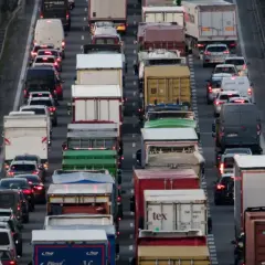 Korek na autostradzie, mnóstwo ciężarówek i samochodów. Widać znaki informujące o zakazie jazdy ciężarówek.