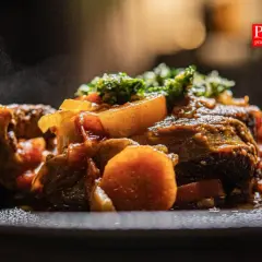 Pyszne, parujące ossobuco wołowe z warzywami na talerzu. Aromatyczne danie, które rozpływa się w ustach.