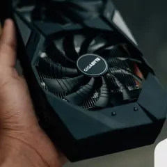 Mano sostiene una tarjeta gráfica Gigabyte, esencial para el rendimiento de tu PC.