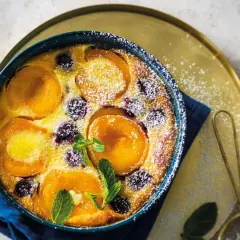 Un délicieux clafoutis abricot, saupoudré de sucre glace et garni de feuilles de menthe fraîche.
