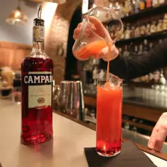 Barman nalewa drink z dzbanka do szklanki z lodem. Obok stoi butelka Campari. To właśnie Campari co to za alkohol?
