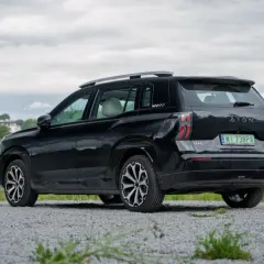 Czarne superauto.pl opinie: GAC Aion V na tle zieleni i chmur.