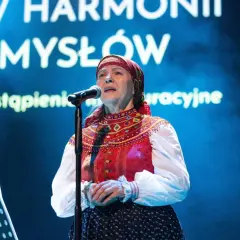 Julia Doszna w tradycyjnym stroju, śpiewająca na scenie.