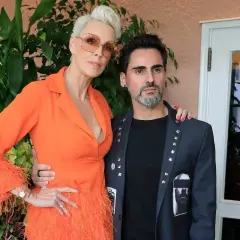 Brigitte Nielsen z mężem, Mattem. Ona w pomarańczowej kreacji z piórami, on w ozdobnej marynarce.