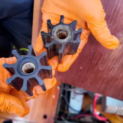 Mani con guanti arancioni mostrano giranti di una pompa, simili a quelle usate per capire come funziona un motore diesel.