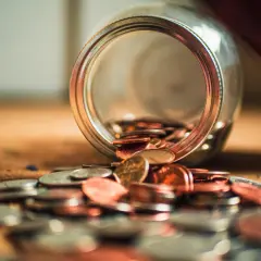 Słoik z monetami rozsypanymi na stole. Jak wyczyścić BIK po upadłości konsumenckiej? Czas na nowy początek finansowy.