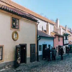 Uliczka Złota w Pradze, z kolorowymi domkami i brukowaną ścieżką, przyciąga turystów.