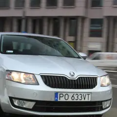 Srebrna Skoda Octavia 1.6 TDI jedzie ulicą miasta.
