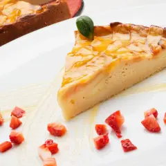 Una rebanada de tarta de manzana tradicional, glaseada y decorada con fresas picadas y una hoja verde.
