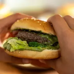 Hände halten einen saftigen Burger mit Hackfleisch. Ein köstliches Beispiel für Hackfleischgerichte, das zum Reinbeißen einlädt.