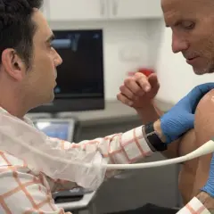 Lekarz wykonuje USG barku pacjenta, diagnozując entezopatię barku.