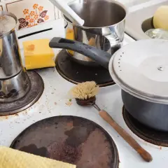 Eine schmutzige alte Ofenplatte mit Kochgeschirr und Reinigungswerkzeugen. Zeit, die alte Ofenplatte zu reinigen und sie wieder zum Glänzen zu bringen.