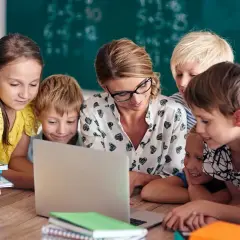 Nauczycielka z uczniami przy laptopie. Szukają informacji, gdzie znaleźć sprawdziany z nowej ery.