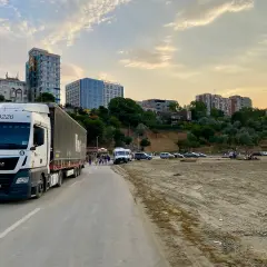 Ciężarówka MAN z naczepą na drodze, w tle budynki i plaża. Idealne miejsce na przerwę i zaplanowanie jadłospisu dla kierowcy tira.