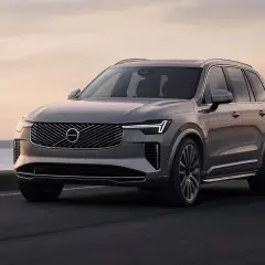 Szary Volvo XC90 jedzie po drodze nad morzem. Sprawdź aktualną volvo xc90 cena.