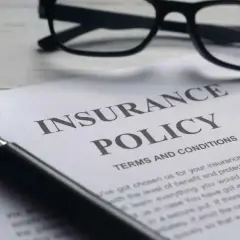 Okulary i lupa nad dokumentem "Insurance Policy". Zastanawiasz się, odszkodowanie za śmierć teścia ile?