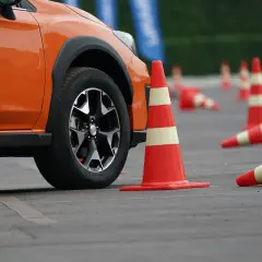 Pomarańczowy samochód na placu manewrowym, przygotowany do egzaminu na prawo jazdy nowe.