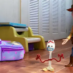 Woody i Forky, bohaterowie filmów dla całej rodziny, stoją obok fioletowego plecaka w pokoju dziecięcym.