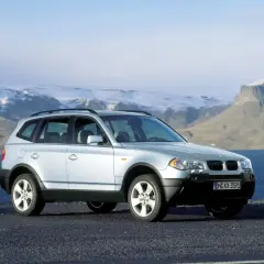 Srebrny BMW X3 E83 na tle gór i morza.
