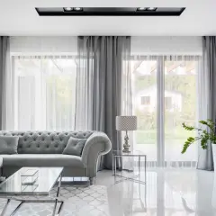 Eleganckie aranżacje okna w salonie: szara sofa, szklane stoliki i zasłony tworzą przytulną atmosferę.