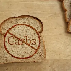 Kromka chleba z przekreślonym napisem "Carbs". Idealne dla osób szukających produktów bez węglowodanów, tabela z nimi może być pomocna.