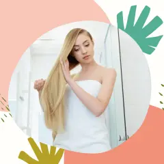 Blondynka owinięta ręcznikiem dotyka swoich długich włosów, które lśnią dzięki zabiegowi zakwaszania.