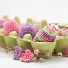 Uova di Pasqua all'uncinetto in un portauova verde, perfette per idee lavoretti con la lana facili e colorati.