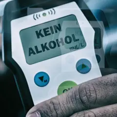 Dłoń trzyma alkomat z napisem "KEIN ALKOHOL" na wyświetlaczu.