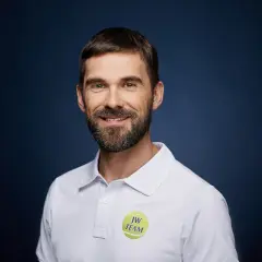 Paweł Habrat, uśmiechnięty mężczyzna z brodą, w białej koszulce polo z logo "JW TEAM".